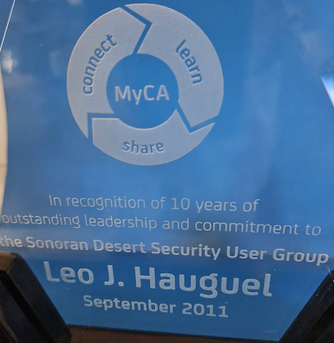 Blue glass award recognizing Leo J. Hauguel for 10 years of leadership in the Sonoran Desert Security User Group, presented by Computer Associates representative Richard Subia in 2011.